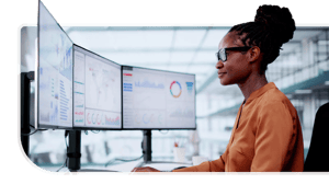 On three computer monitors, a woman views artificial intelligence and machine learning data.