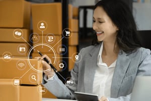 An inventory planner looks at a tablet surrounded by boxes.