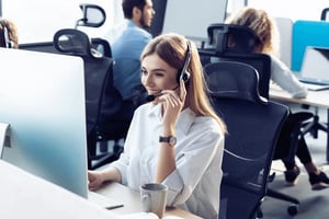 A customer service representative smiles in a call center.