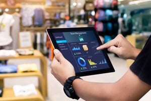 Retail store manager holding up a tablet that's displaying performance data.