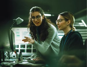 Two fulfillment team members pointing at a computer screen working on order promising workflows.