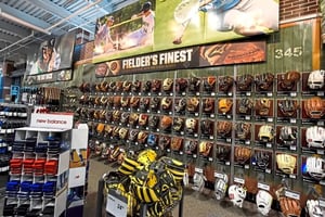 A wall filled with baseball mitts in a sporting goods retail store.