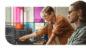 A woman points to code on a desktop screen beside her coworker.